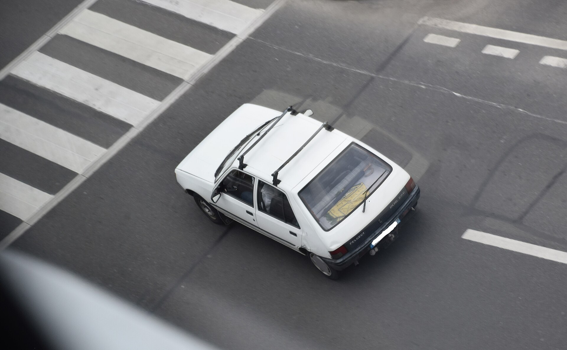 Une Peugeot 205 blanche vue d en haut, sur une chaussee.
