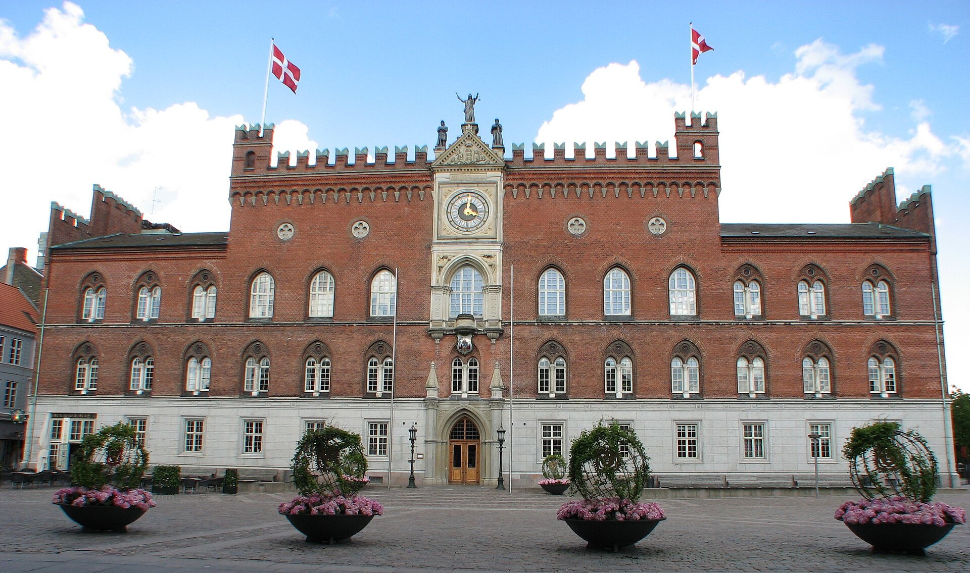 L hotel de ville d Odense, en brique rouge, avec des drapeaux danois.