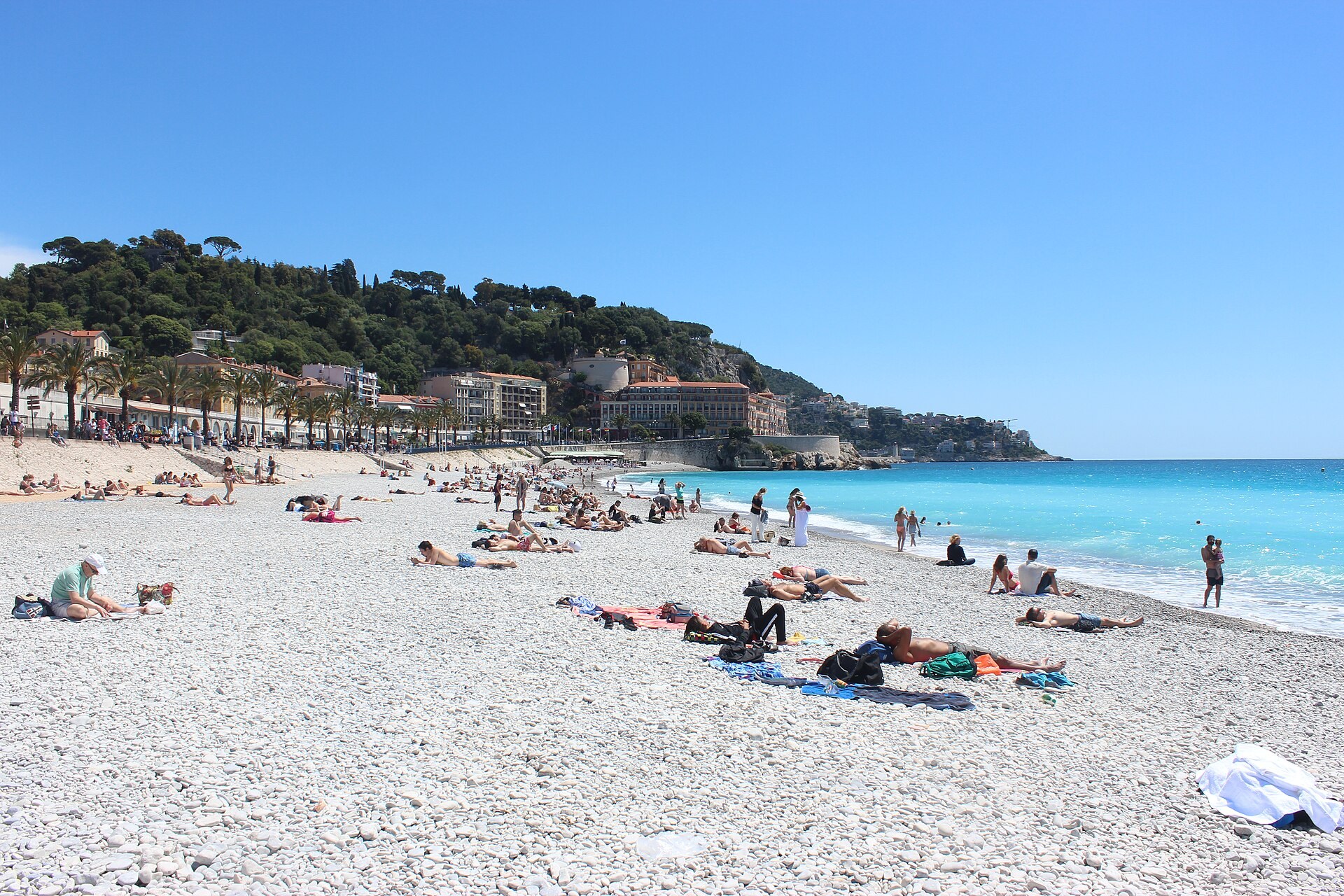 La plage de galets de la promenade des Anglais a Nice, sous un ciel bleu.
