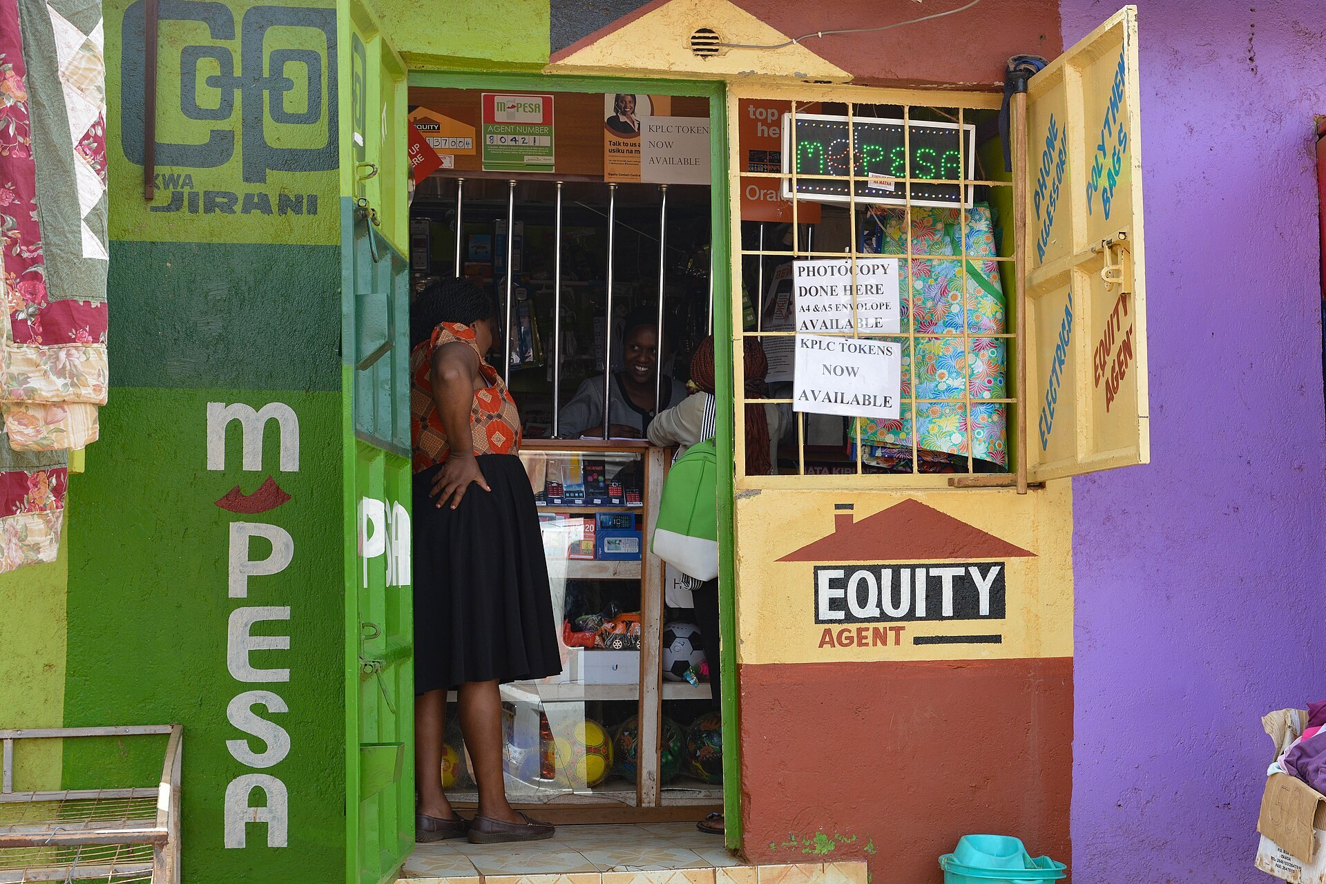 Une petite boutique peinte en vert et violet affichant M-PESA et Equity Agent, a Nairobi.