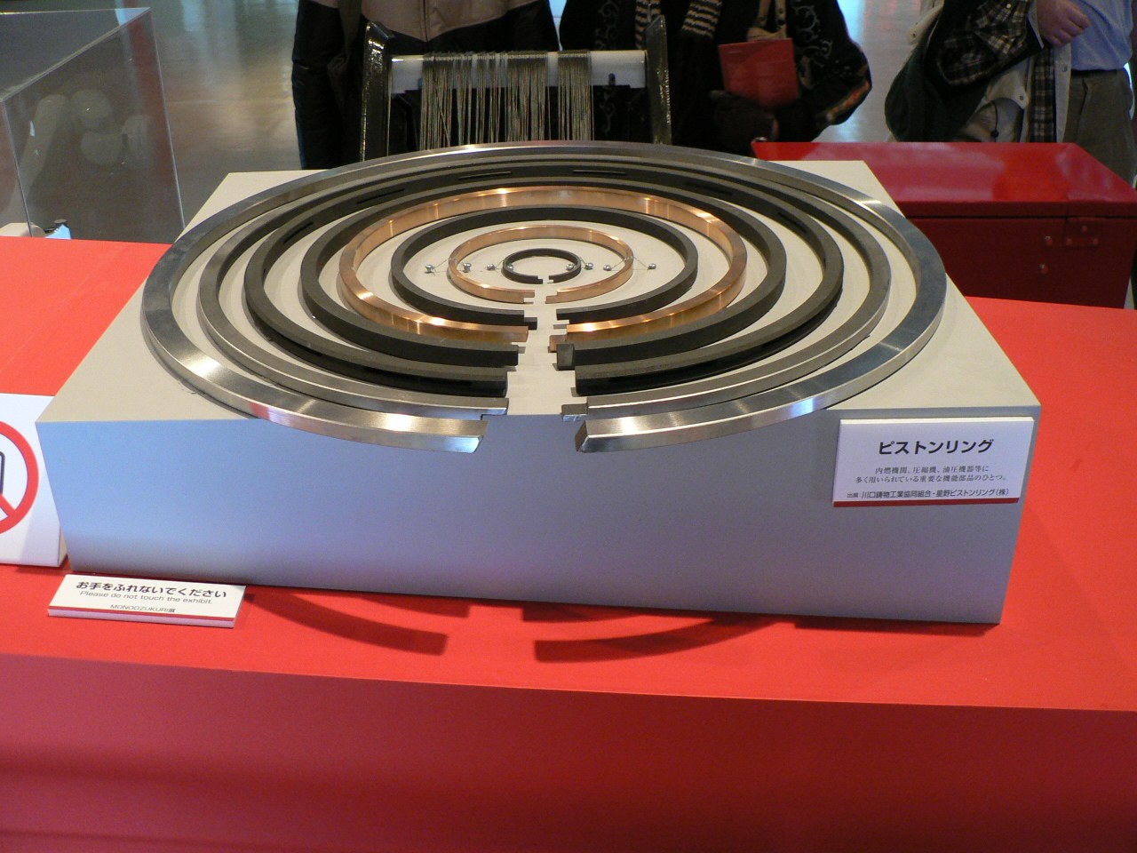 Concentric piston rings displayed on a red stand.