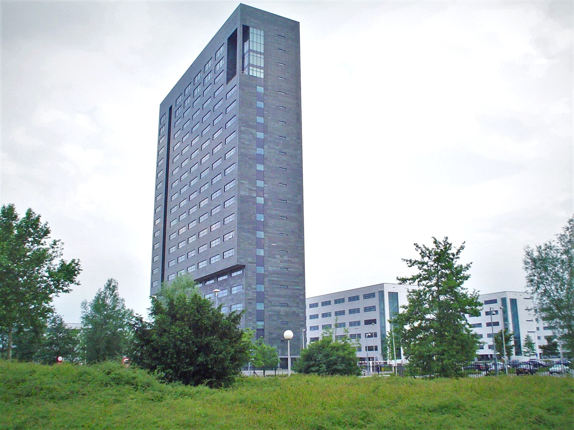 The tower of ASML's headquarters in Veldhoven, surrounded by trees.