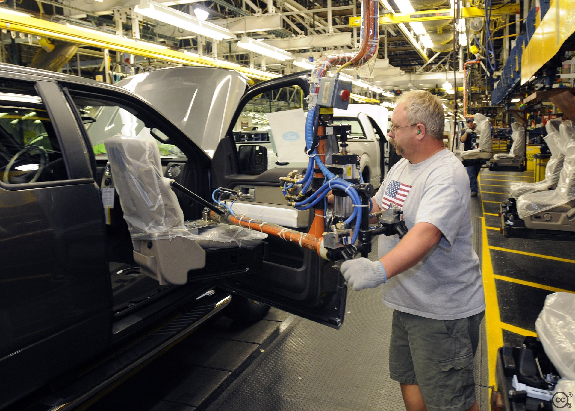 A worker installs a seat in a pickup truck on an assembly line.