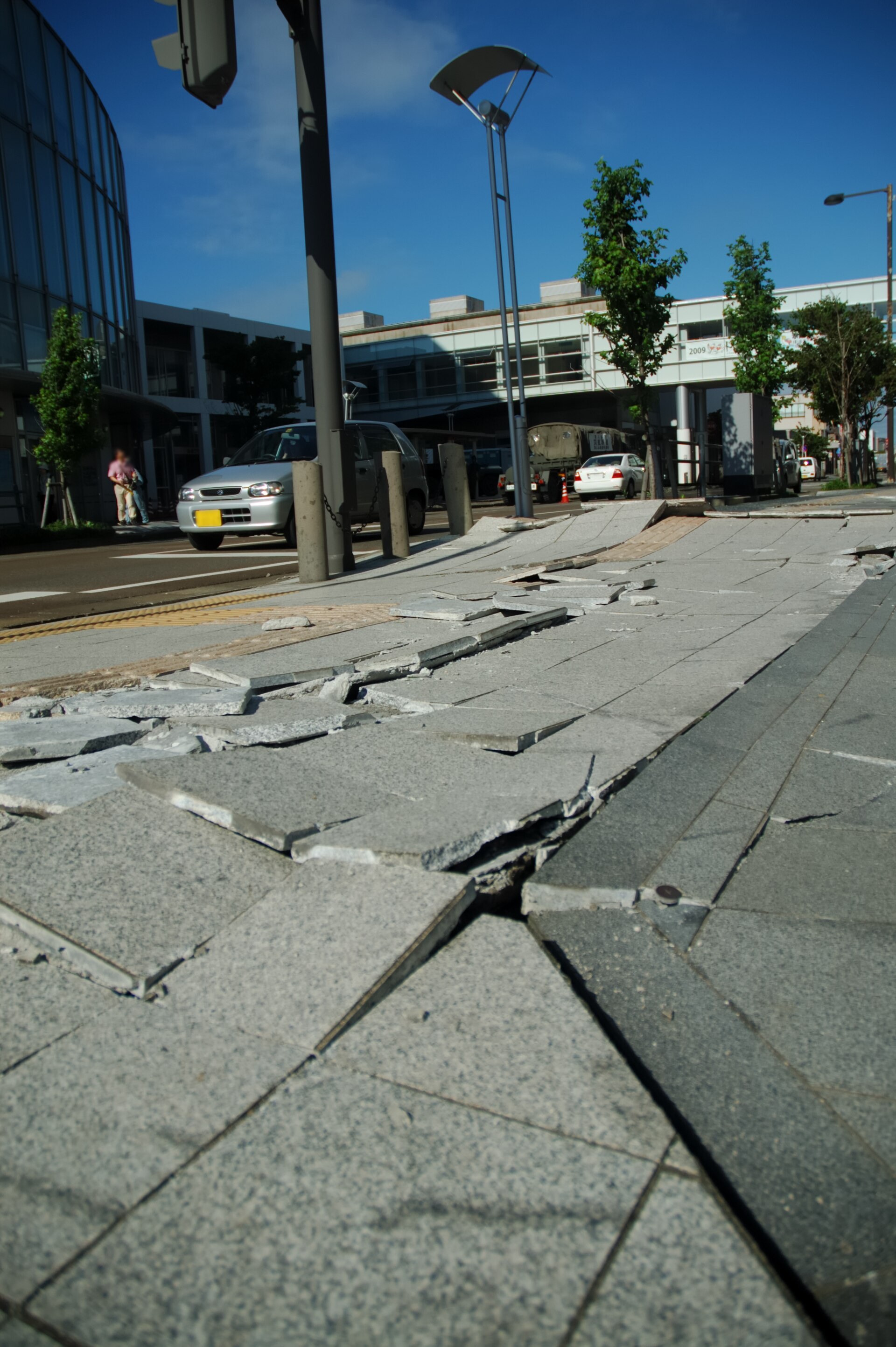 A sidewalk with lifted, cracked paving slabs in a street in Kashiwazaki.