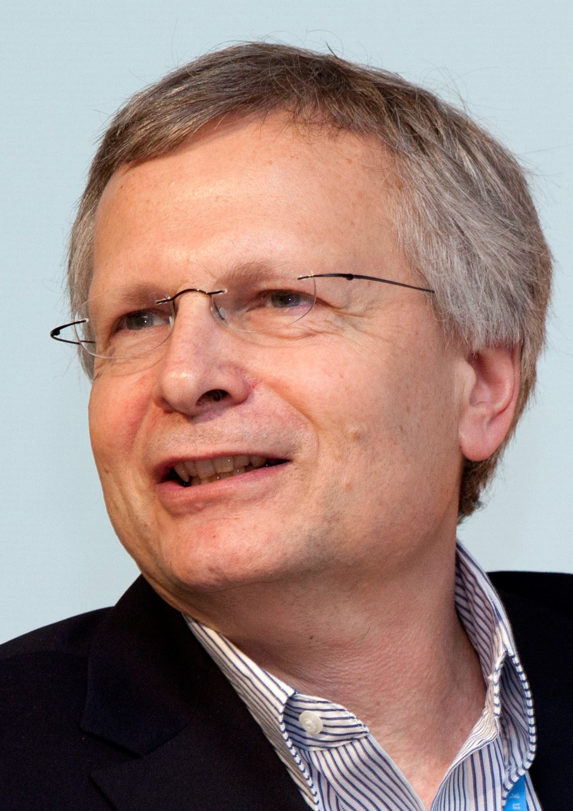 Portrait of the economist Dani Rodrik, smiling, in a dark jacket.