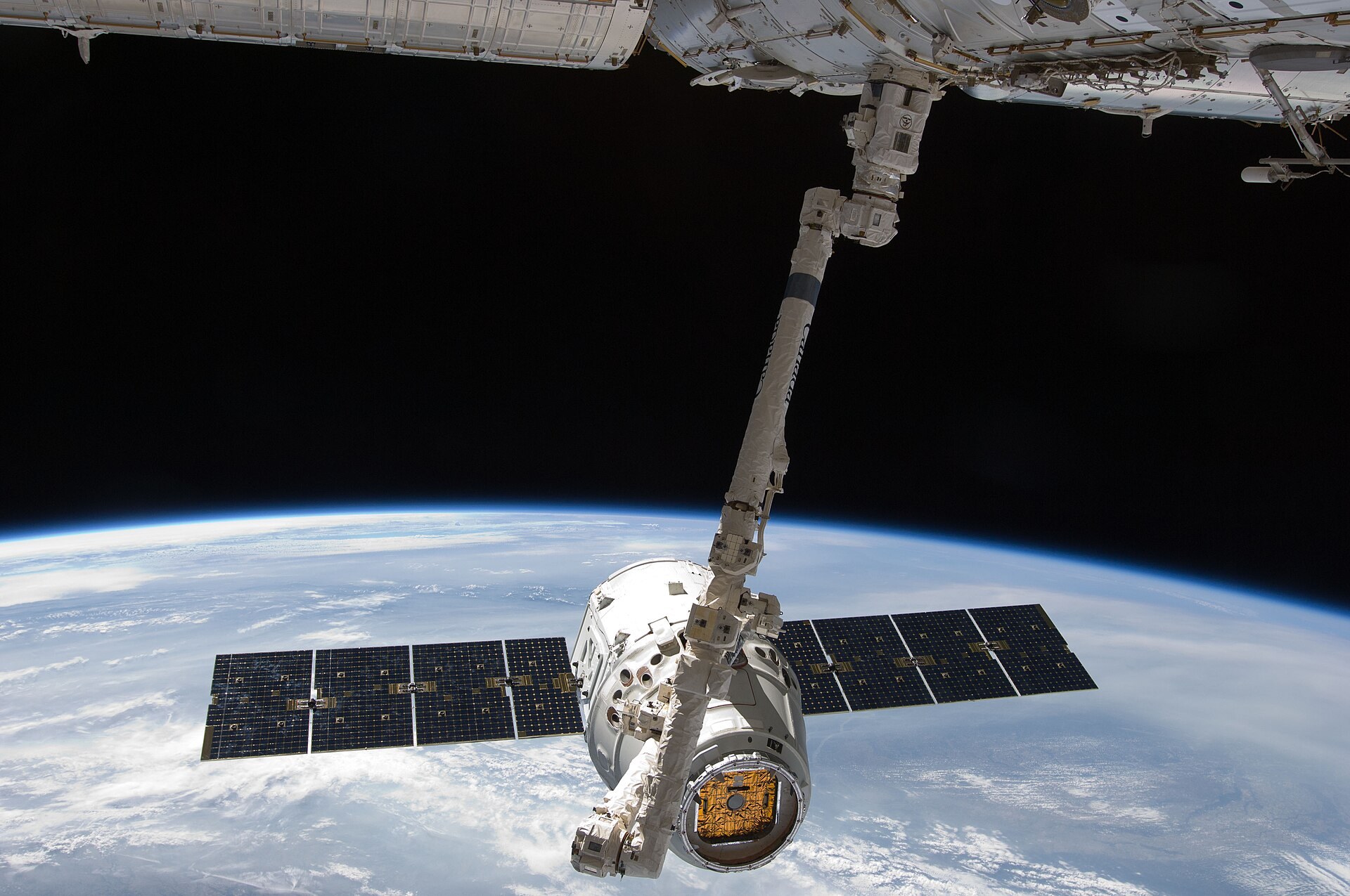 Le bras robotique de la station saisit la capsule Dragon au-dessus de la Terre.