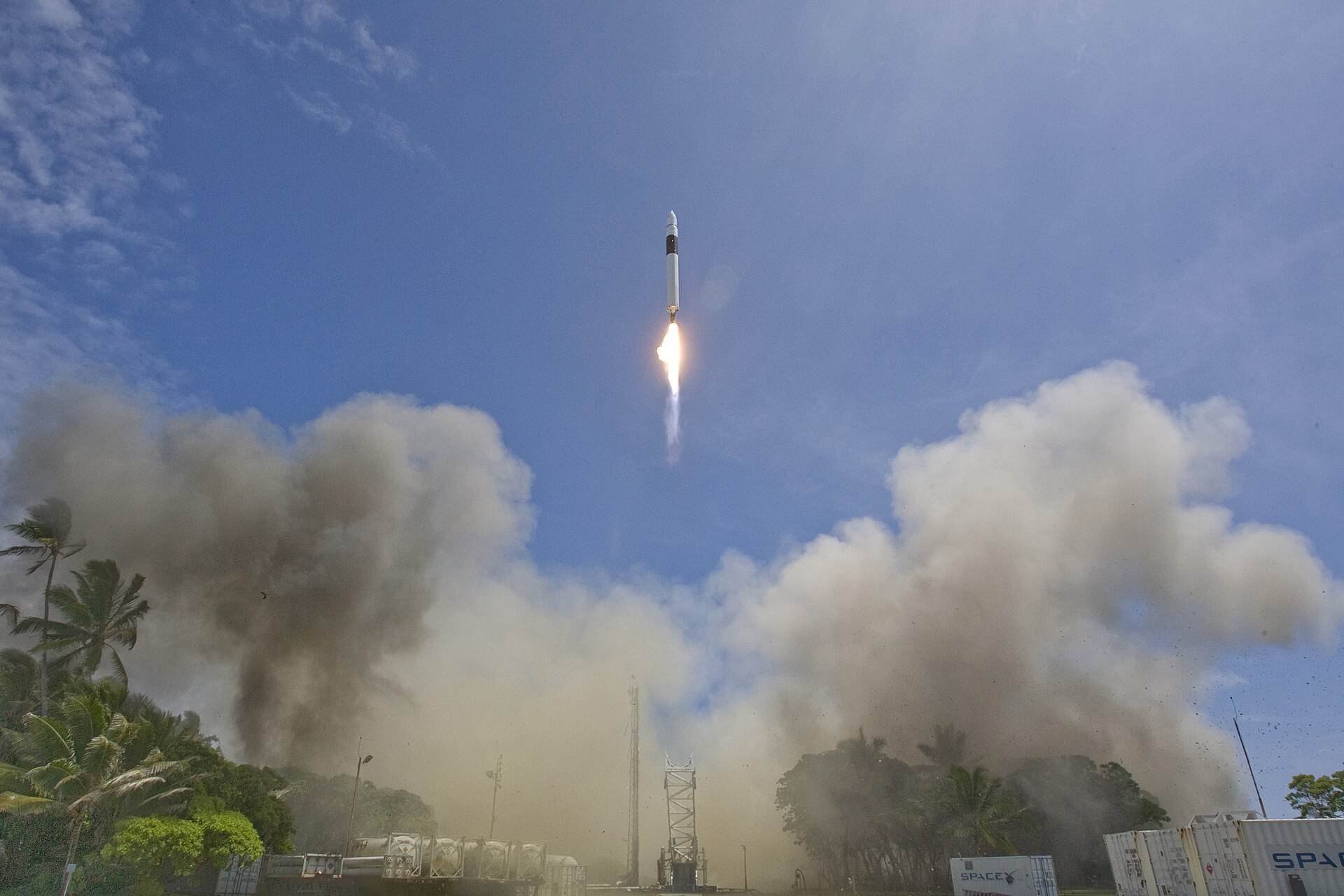 Une petite fusee Falcon 1 decolle d une ile tropicale dans un nuage de fumee.
