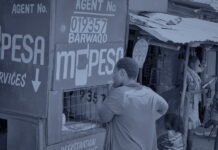 Politics comes down into the company and shapes the product Un kiosque d'agent de paiement mobile dans une rue en terre, une cliente au guichet, en bichromie bleu sombre