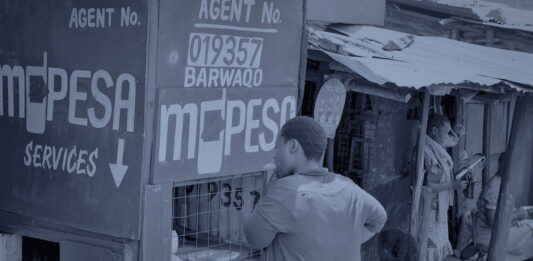 Politics comes down into the company and shapes the product Un kiosque d'agent de paiement mobile dans une rue en terre, une cliente au guichet, en bichromie bleu sombre