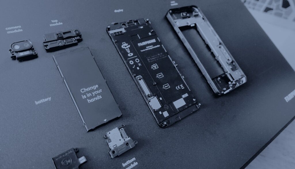 Les modules détachés d’un téléphone Fairphone 3 posés sur un présentoir noir, en bichromie bleu sombre