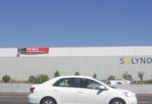 Quand l’État se retire, le risque passe sur votre bilan Le bâtiment de Solyndra à Fremont, en Californie, vu depuis l'autoroute, avec un panneau « for sale » posé sur la façade et l'enseigne de l'entreprise encore en place