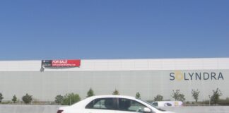 Quand l’État se retire, le risque passe sur votre bilan Le bâtiment de Solyndra à Fremont, en Californie, vu depuis l'autoroute, avec un panneau « for sale » posé sur la façade et l'enseigne de l'entreprise encore en place