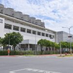 L'usine Fab 18 de TSMC dans le parc scientifique du sud de Taïwan, vue depuis la rue, avec ses tours de refroidissement sur le toit et des camions à l'entrée