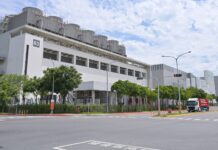 Nvidia ne doit rien à personne, sauf le sol sur lequel elle est bâtie L'usine Fab 18 de TSMC dans le parc scientifique du sud de Taïwan, vue depuis la rue, avec ses tours de refroidissement sur le toit et des camions à l'entrée