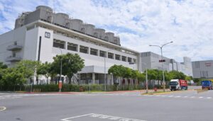 L'usine Fab 18 de TSMC dans le parc scientifique du sud de Taïwan, vue depuis la rue, avec ses tours de refroidissement sur le toit et des camions à l'entrée